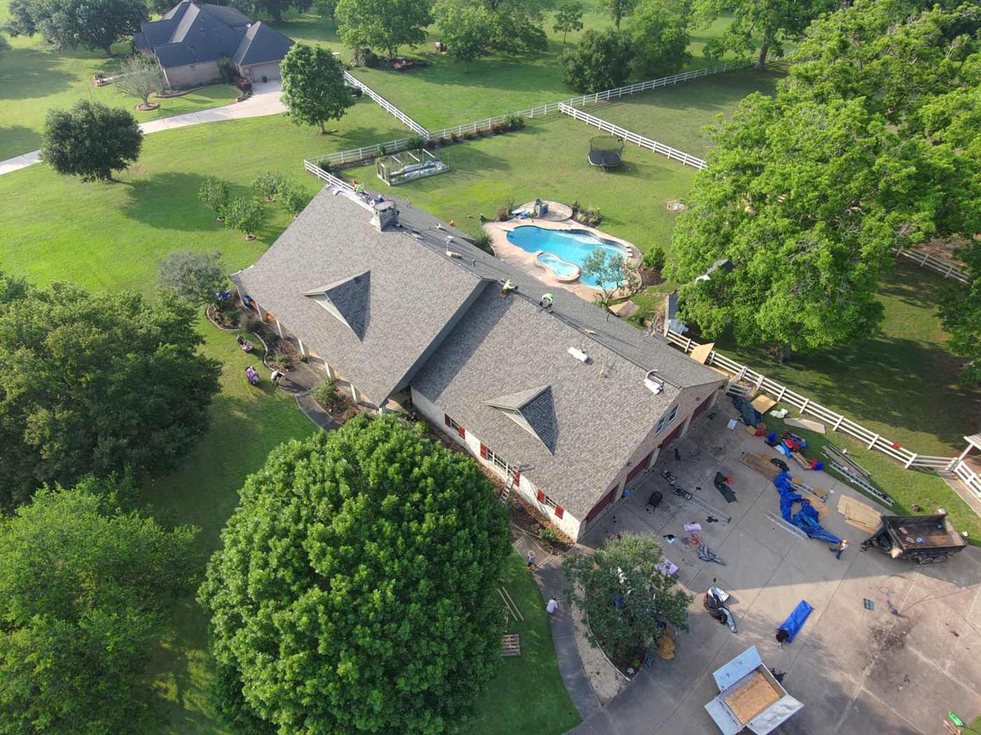 Completed architectural shingle roof on a large ranch-style home seen from a drone