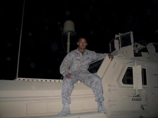 Marine seated on an MRAP at a forward operating base at night
