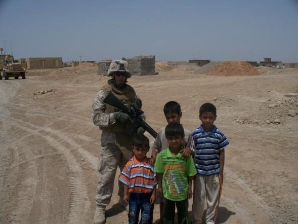 Marine standing with local Iraqi children during a patrol
