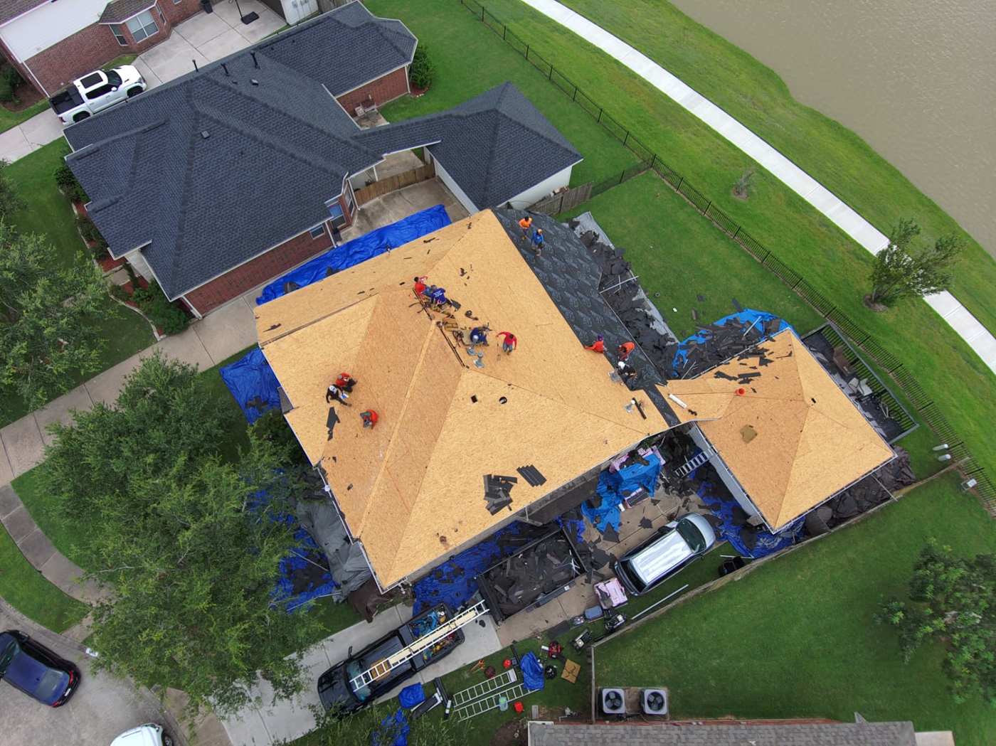 Aerial drone view of a Houston-area home stripped to bare roof decking during a full tear-off