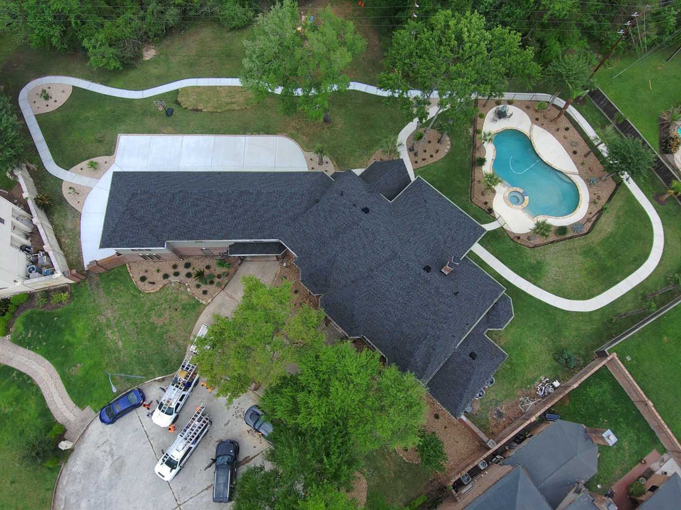 Top-down drone inspection photo of a charcoal shingle roof on a Houston-area home with a pool