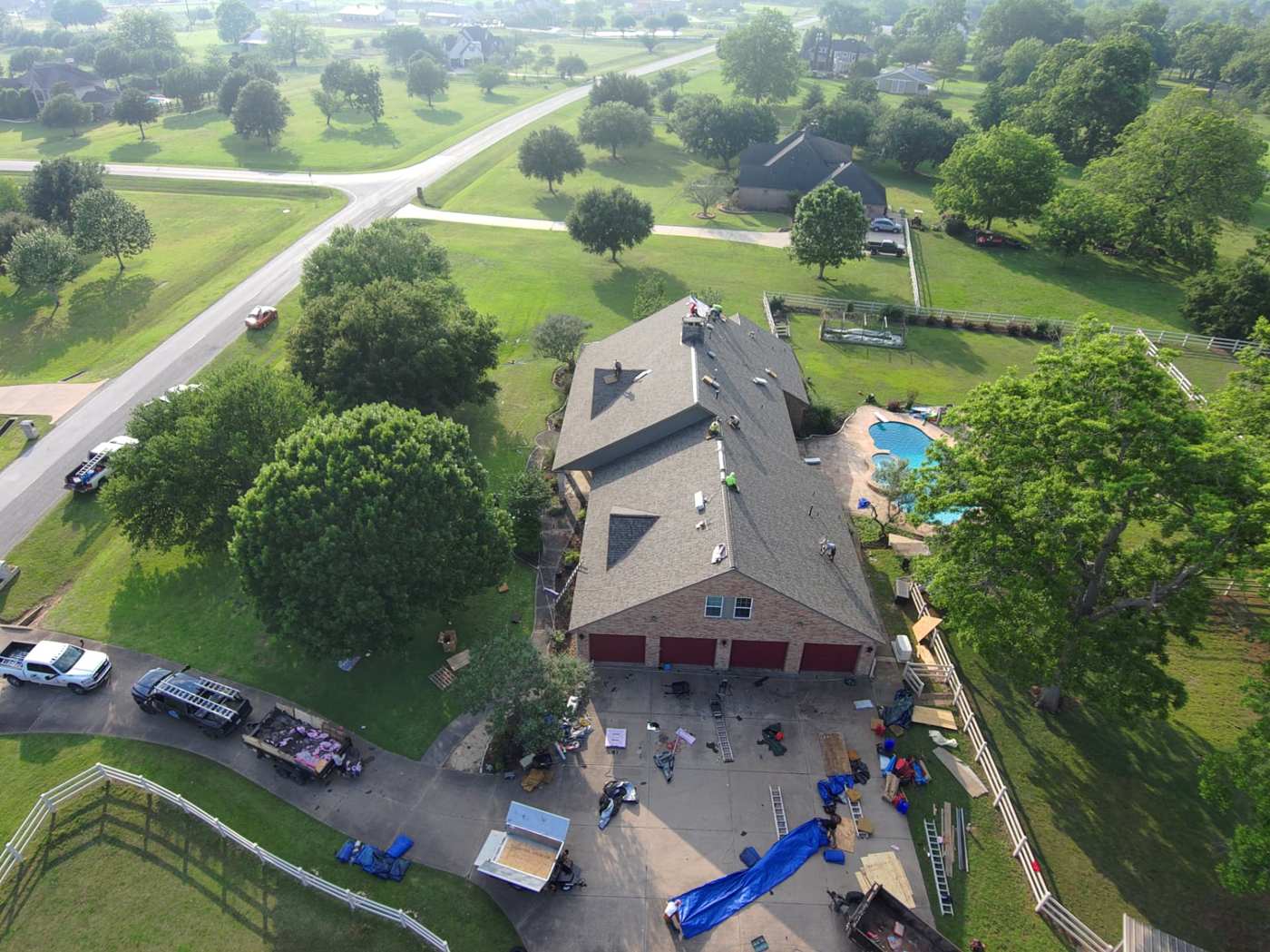 Drone photo of an acreage home with roofing materials staged in the driveway