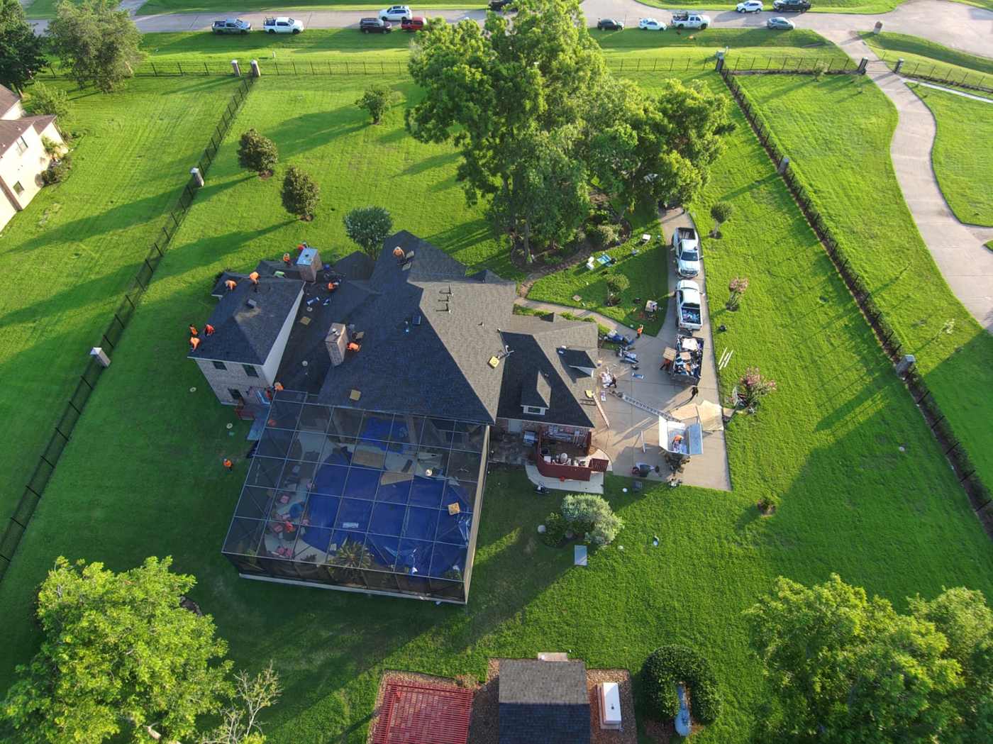 Aerial view of a home with a screened pool enclosure tarped during a roof replacement