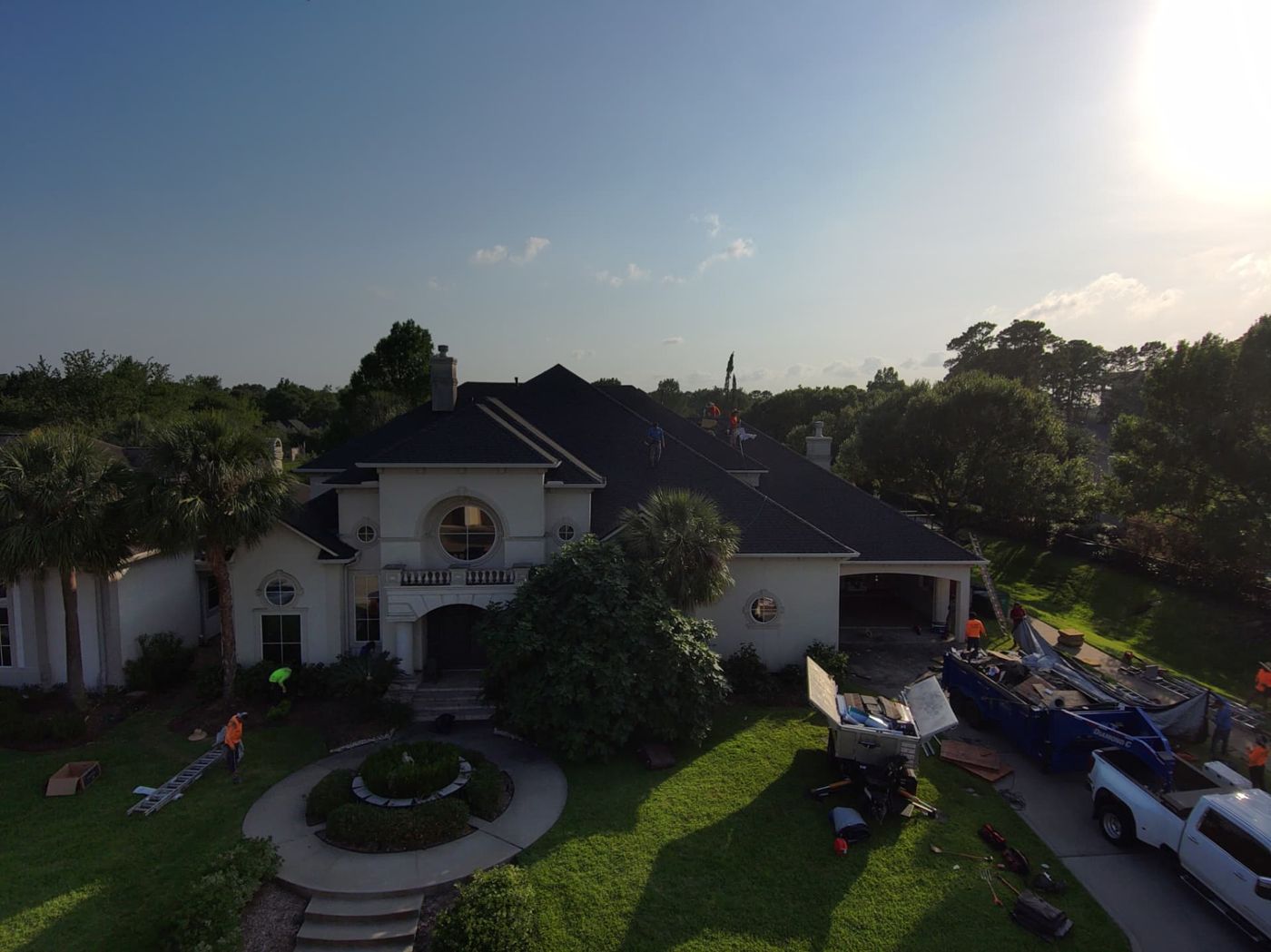 Completed dark shingle roof on a large white stucco estate home